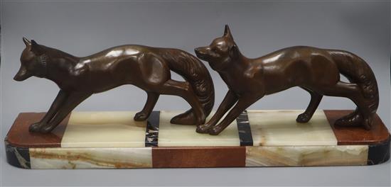 A French Art Deco bronzed metal group of two foxes, on hardstone base length 60cm